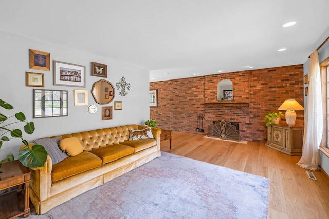 living room featuring recessed lighting, brick wall, wood finished floors, and a fireplace