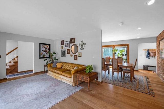 living area with light wood-style floors, stairs, and baseboards