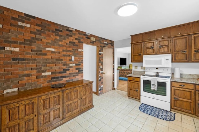 kitchen with brown cabinetry, light tile patterned floors, brick wall, and white appliances