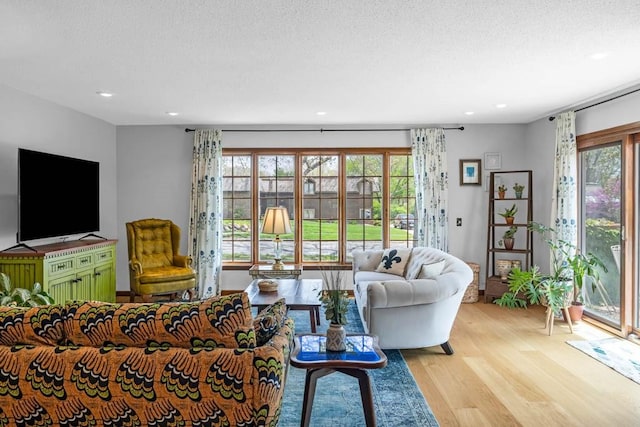 living area with recessed lighting, light wood-type flooring, and a textured ceiling