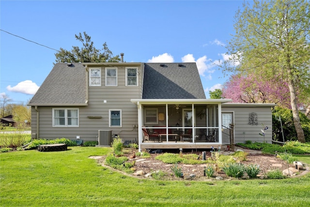 back of property with a sunroom, a shingled roof, central AC, and a yard