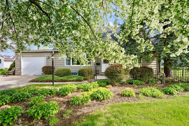 obstructed view of property with concrete driveway, an attached garage, and fence