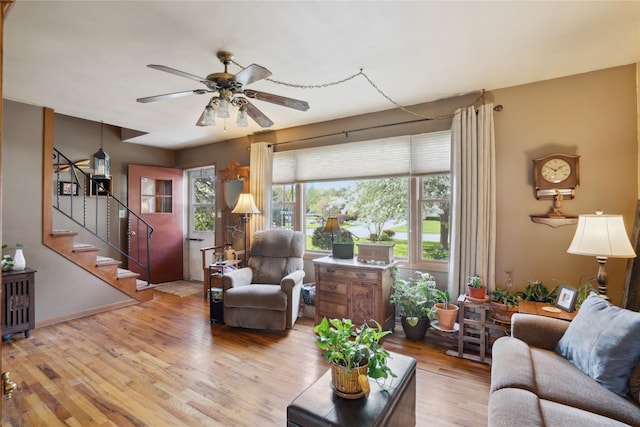 living area with ceiling fan, wood finished floors, and stairway