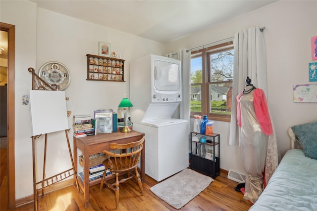 laundry room featuring laundry area, visible vents, wood finished floors, and stacked washer and clothes dryer