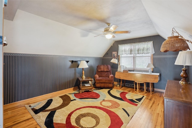 sitting room with ceiling fan, wood-type flooring, and vaulted ceiling