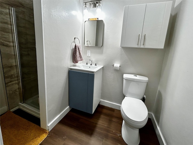 3825 15th St, Des Moines, IA 50313 - bathroom with vanity, baseboards, wood finished floors, a shower stall, and toilet