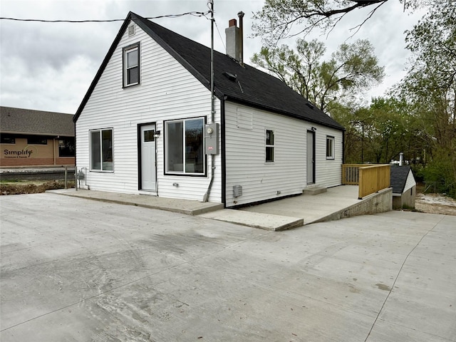 4825 SW 9th St, Des Moines, IA 50315 - back of property with a chimney, a patio, an outbuilding, roof with shingles, and a storage unit