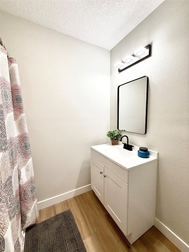 4825 SW 9th St, Des Moines, IA 50315 - full bathroom with wood finished floors, a textured ceiling, baseboards, and vanity
