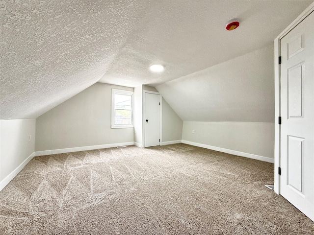 4825 SW 9th St, Des Moines, IA 50315 - bonus room with baseboards, carpet floors, vaulted ceiling, and a textured ceiling