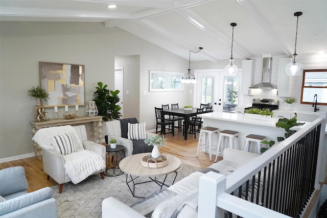 living area featuring light wood-style floors, baseboards, vaulted ceiling with beams, and recessed lighting