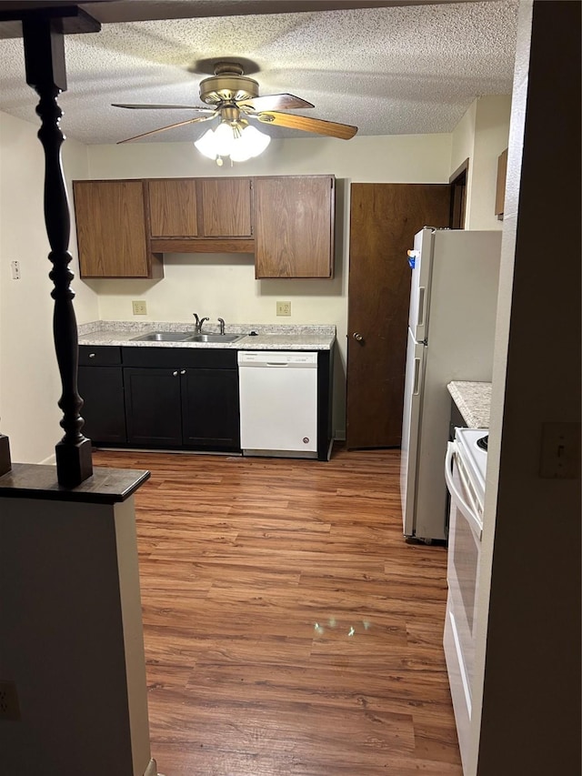 4665 E Oakwood Dr, Pleasant Hill, IA 50327 - kitchen with light wood finished floors, a ceiling fan, white appliances, and a textured ceiling