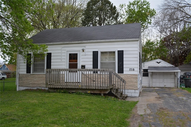 view of front facade with stone siding, fence, aphalt driveway, a front lawn, and an outdoor structure