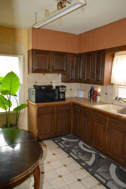 kitchen with a sink, light floors, black microwave, light countertops, and decorative backsplash