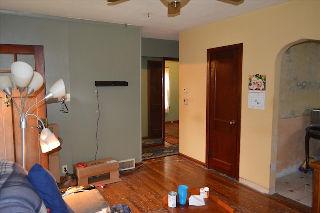 living area featuring wood finished floors, visible vents, baseboards, ceiling fan, and arched walkways