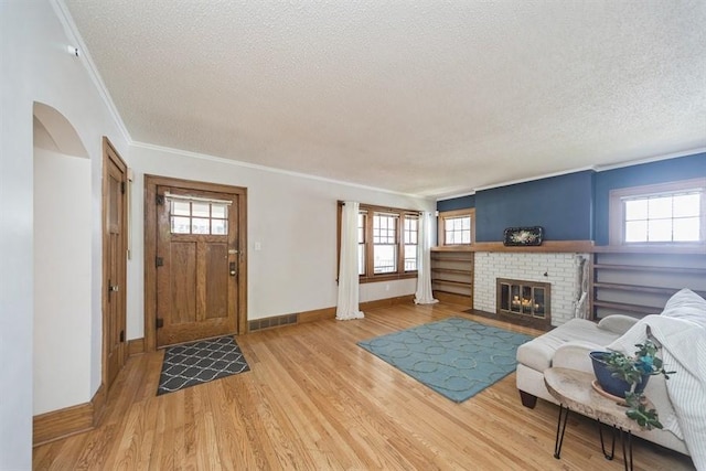 entrance foyer featuring ornamental molding, a textured ceiling, visible vents, light wood finished floors, and baseboards