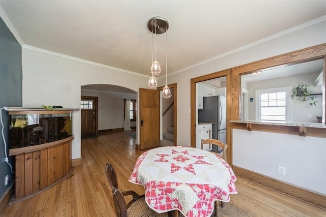 dining space with light wood-type flooring, stairway, baseboards, and arched walkways