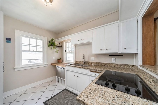 kitchen featuring baseboards, light tile patterned flooring, a sink, white cabinetry, and black electric stovetop