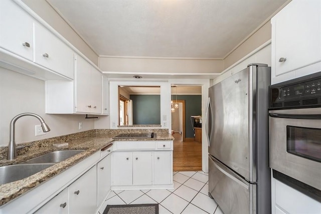kitchen with a sink, stainless steel appliances, white cabinets, light tile patterned floors, and stone counters