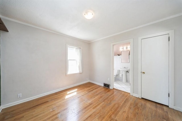 unfurnished bedroom featuring crown molding, visible vents, baseboards, and wood-type flooring