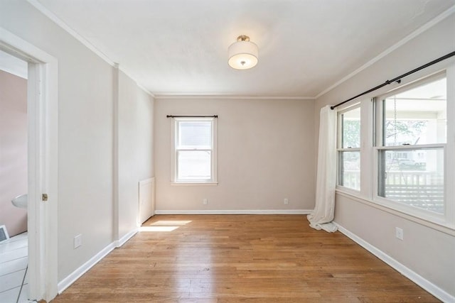 spare room with light wood finished floors, ornamental molding, baseboards, and plenty of natural light