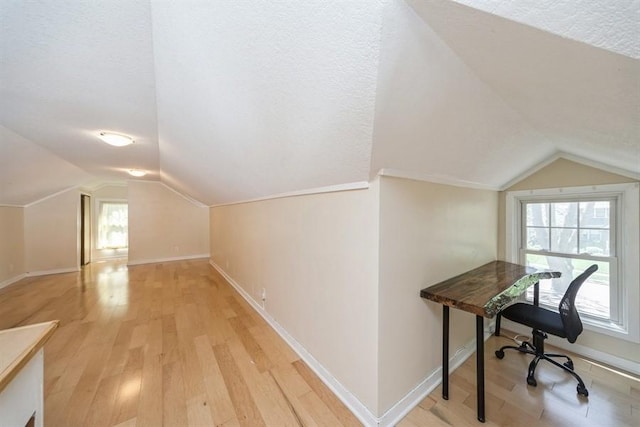 bonus room with a textured ceiling, baseboards, light wood-style flooring, and lofted ceiling