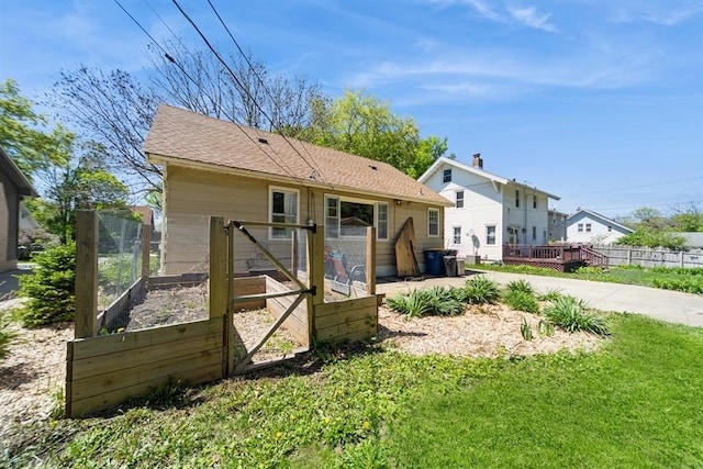 back of property with a yard, a deck, a vegetable garden, and fence