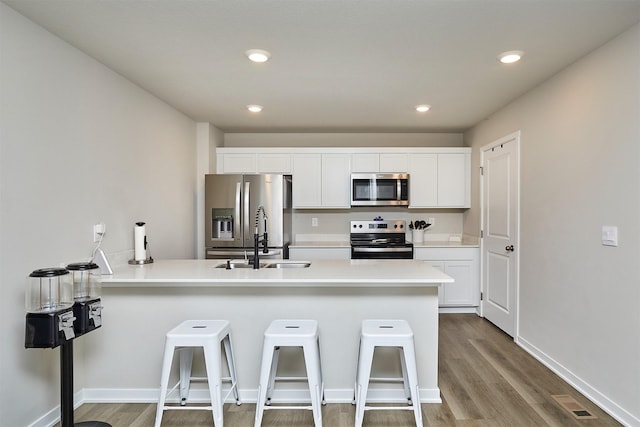 1150 NW Williamsburg Ln, Waukee, IA 50263 - kitchen with appliances with stainless steel finishes, a sink, wood finished floors, a peninsula, and white cabinets