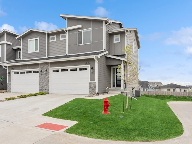 view of property with stone siding, an attached garage, cooling unit, fence, and a front lawn