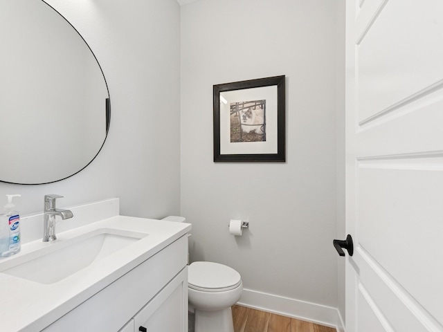 bathroom featuring vanity, wood finished floors, baseboards, and toilet