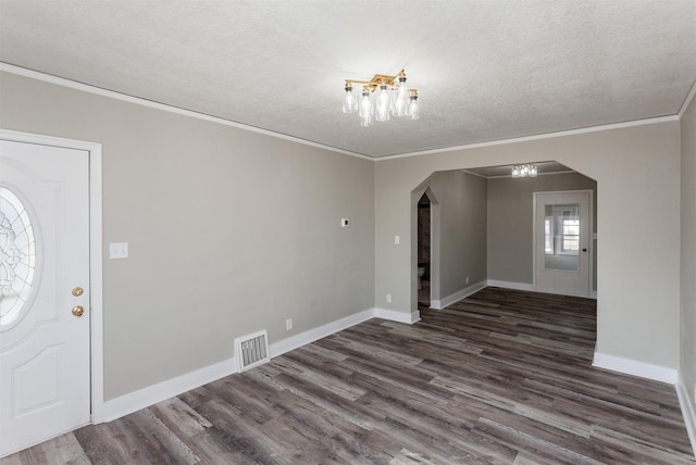 foyer featuring arched walkways, dark wood finished floors, visible vents, and a textured ceiling