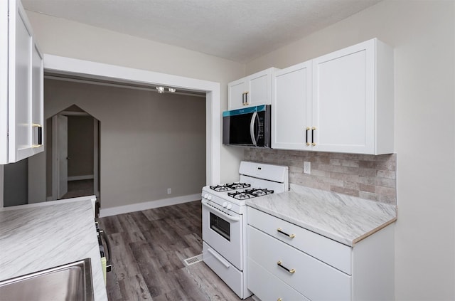kitchen featuring gas range gas stove, white cabinetry, stainless steel microwave, and light countertops