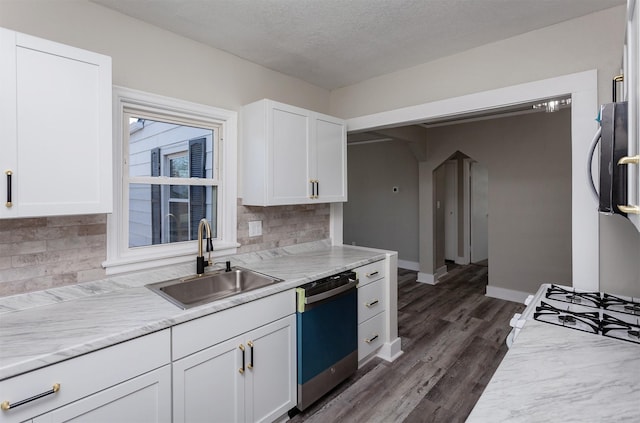 kitchen featuring backsplash, dishwasher, white cabinets, and a sink