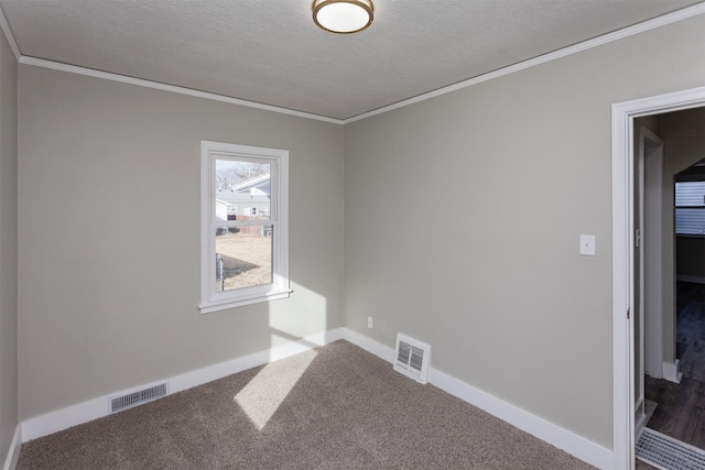 carpeted spare room with crown molding, a textured ceiling, baseboards, and visible vents