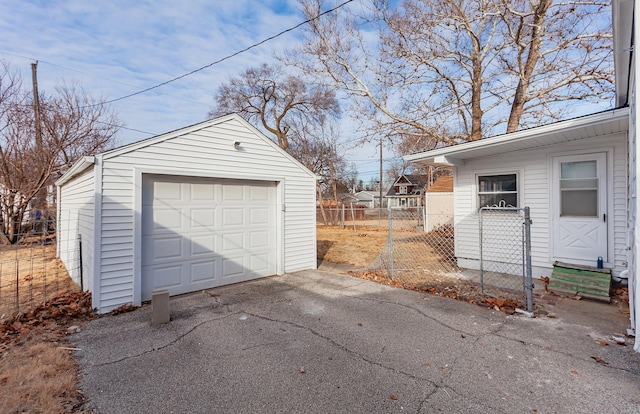 detached garage featuring driveway and fence