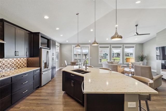 kitchen featuring a sink, open floor plan, vaulted ceiling, tasteful backsplash, and dark wood-style floors