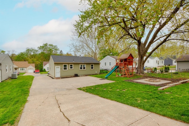 rear view of house featuring central air condition unit, fence, a residential view, a yard, and a playground