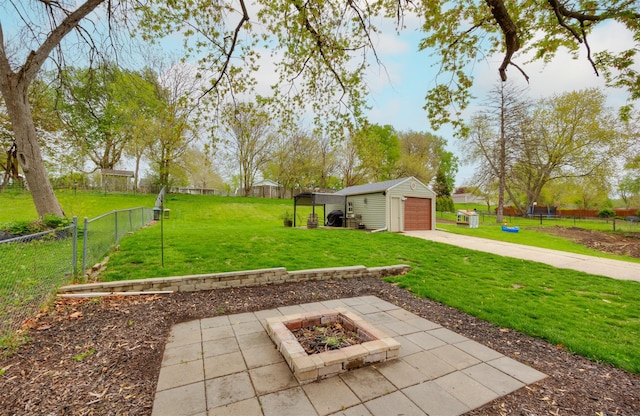 view of yard featuring an outdoor fire pit, an outbuilding, fence, and a garage