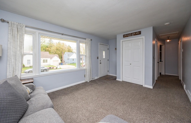 carpeted living room featuring attic access and baseboards