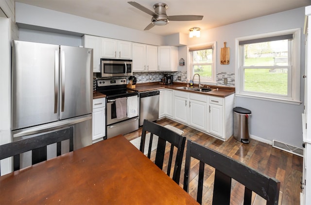 kitchen featuring ceiling fan, a sink, visible vents, stainless steel appliances, and tasteful backsplash