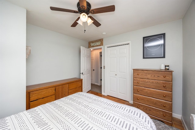 bedroom featuring ceiling fan, a closet, baseboards, and wood finished floors