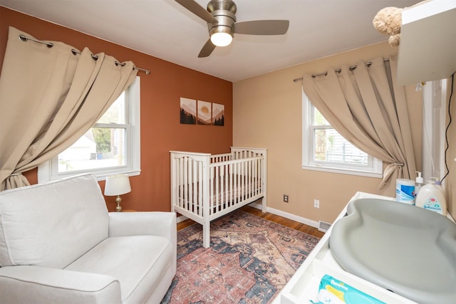 bedroom featuring ceiling fan, baseboards, and wood finished floors