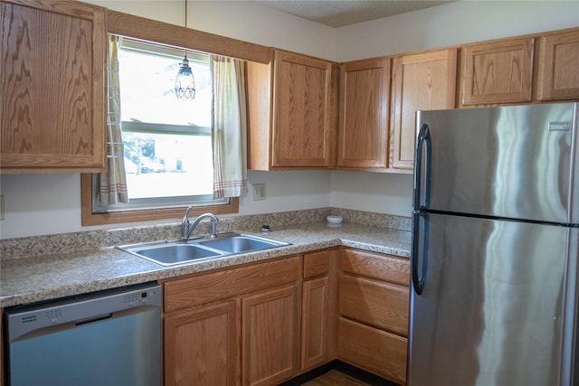 kitchen featuring freestanding refrigerator, dishwashing machine, light countertops, and a sink