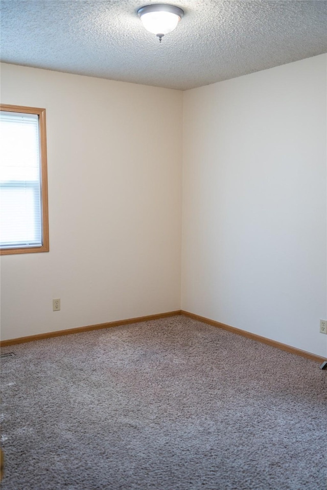 carpeted spare room with a textured ceiling and baseboards