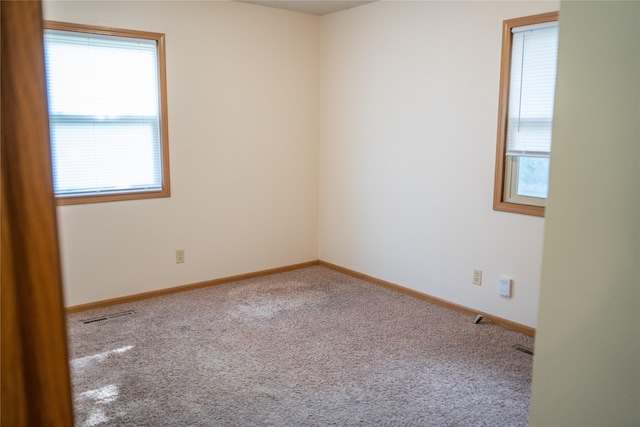 unfurnished room featuring carpet, a wealth of natural light, and visible vents