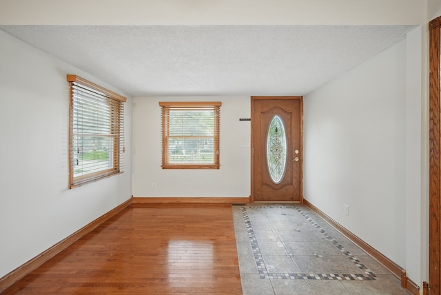 entrance foyer with a textured ceiling, baseboards, and plenty of natural light