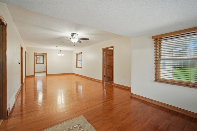 empty room with a ceiling fan, light wood-style floors, a textured ceiling, and baseboards