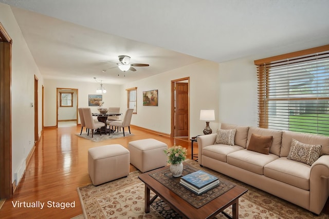 living area with baseboards, ceiling fan, and wood finished floors