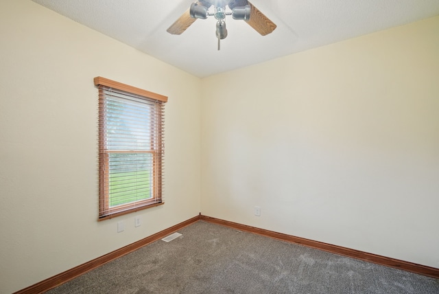 carpeted empty room with visible vents, baseboards, and a ceiling fan