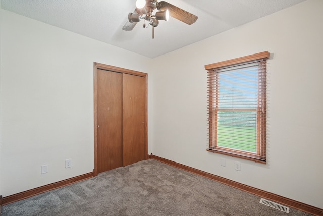 unfurnished bedroom with a ceiling fan, a closet, carpet, baseboards, and visible vents