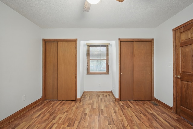 unfurnished bedroom featuring light wood finished floors, two closets, and baseboards